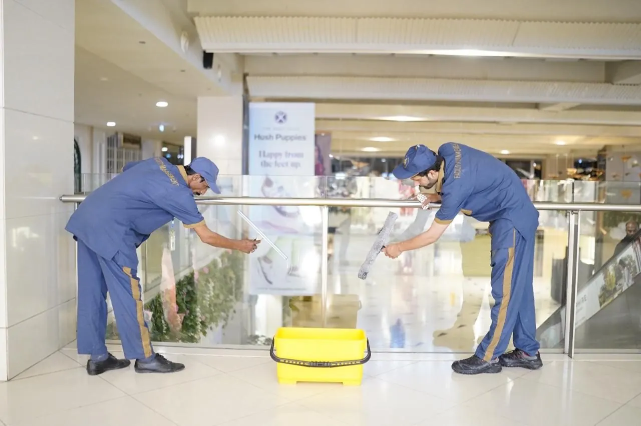 Feroza staff cleaning glass balustrades in a mall atrium