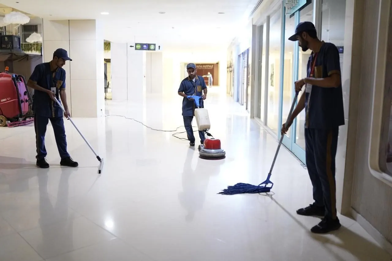 Janitorial crew wet-mopping a shopping mall corridor